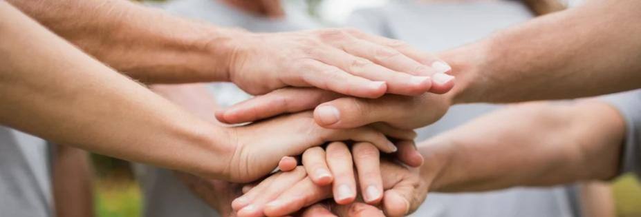 Happy volunteer family putting their hands together on a sunny day - cropped